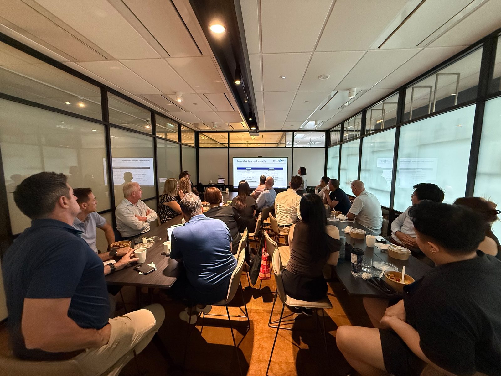 A full room of internationally mobile investors at the On Invest and Expat UK Tax Lunch & Learn in Singapore, with Amy Kwok presenting a slide comparing personal and company ownership of UK property